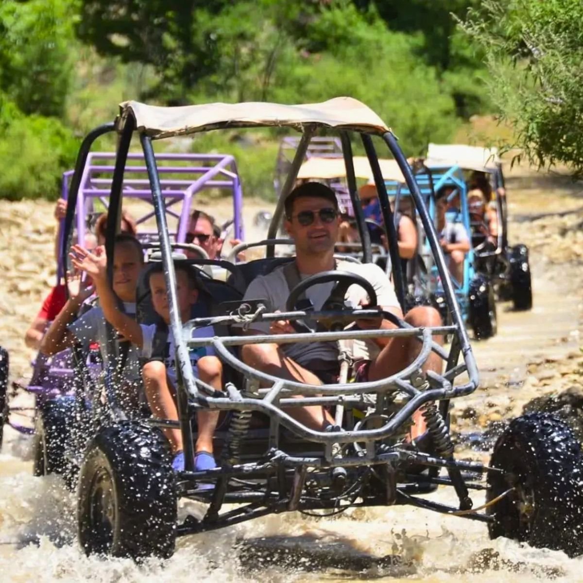 Family buggy convoy crossing rocky riverbed