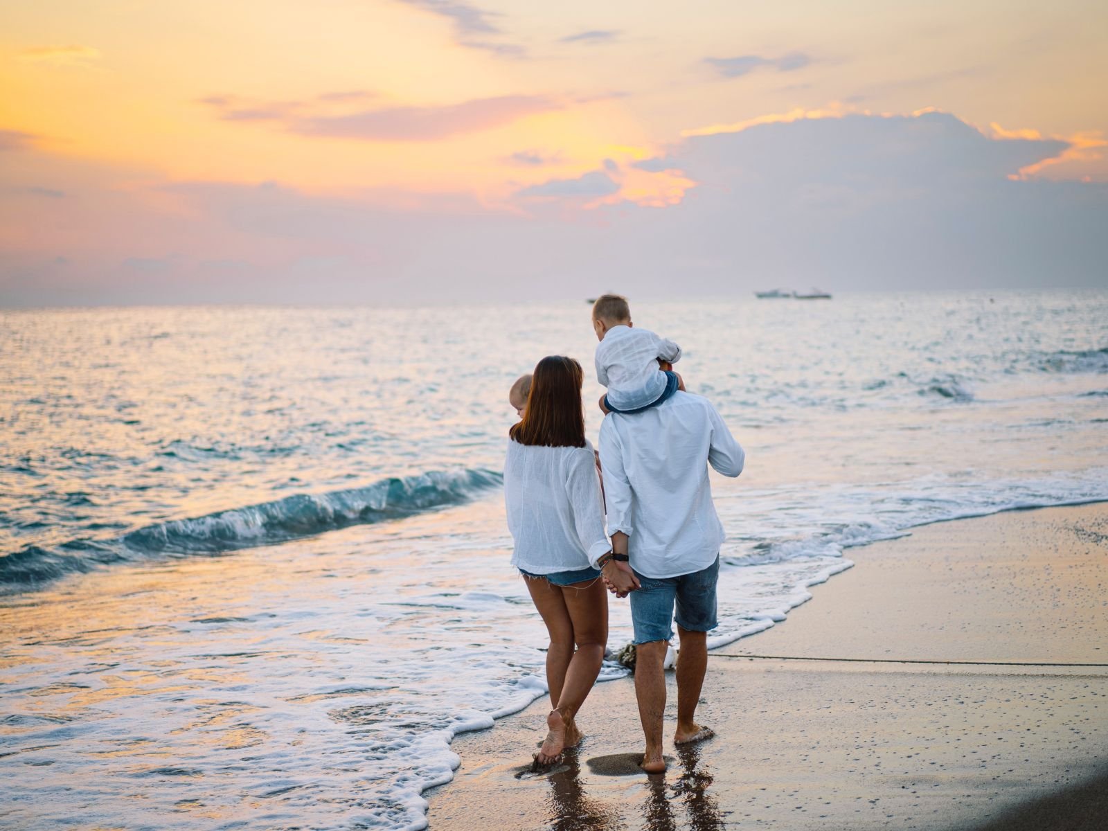 Relaxed family walking along the beach at golden hour
