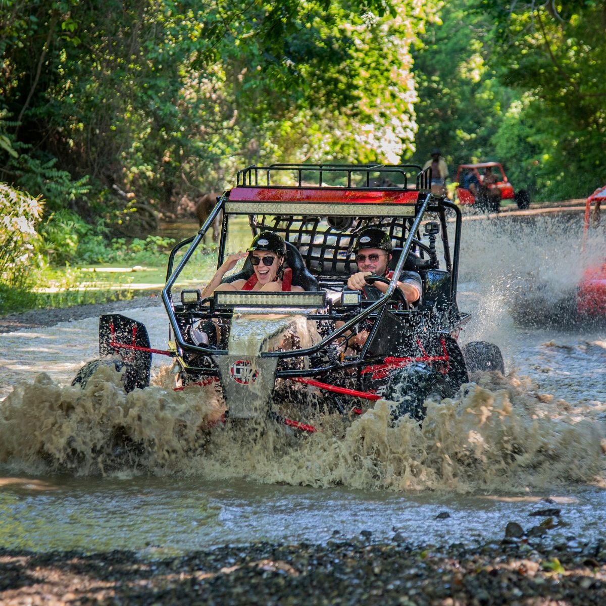 Red buggy driving through forest stream with big splash