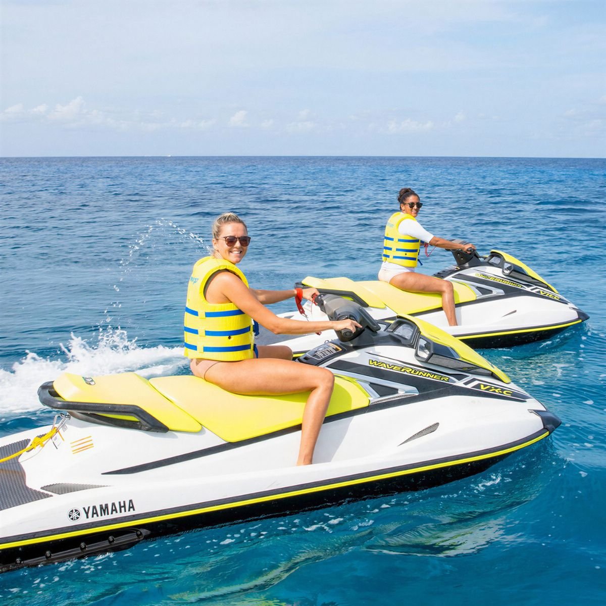 Two women riding jet skis on the sea