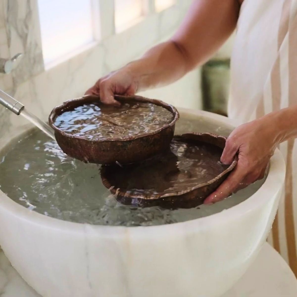 Traditional copper hamam bowls (tas) being filled with warm water