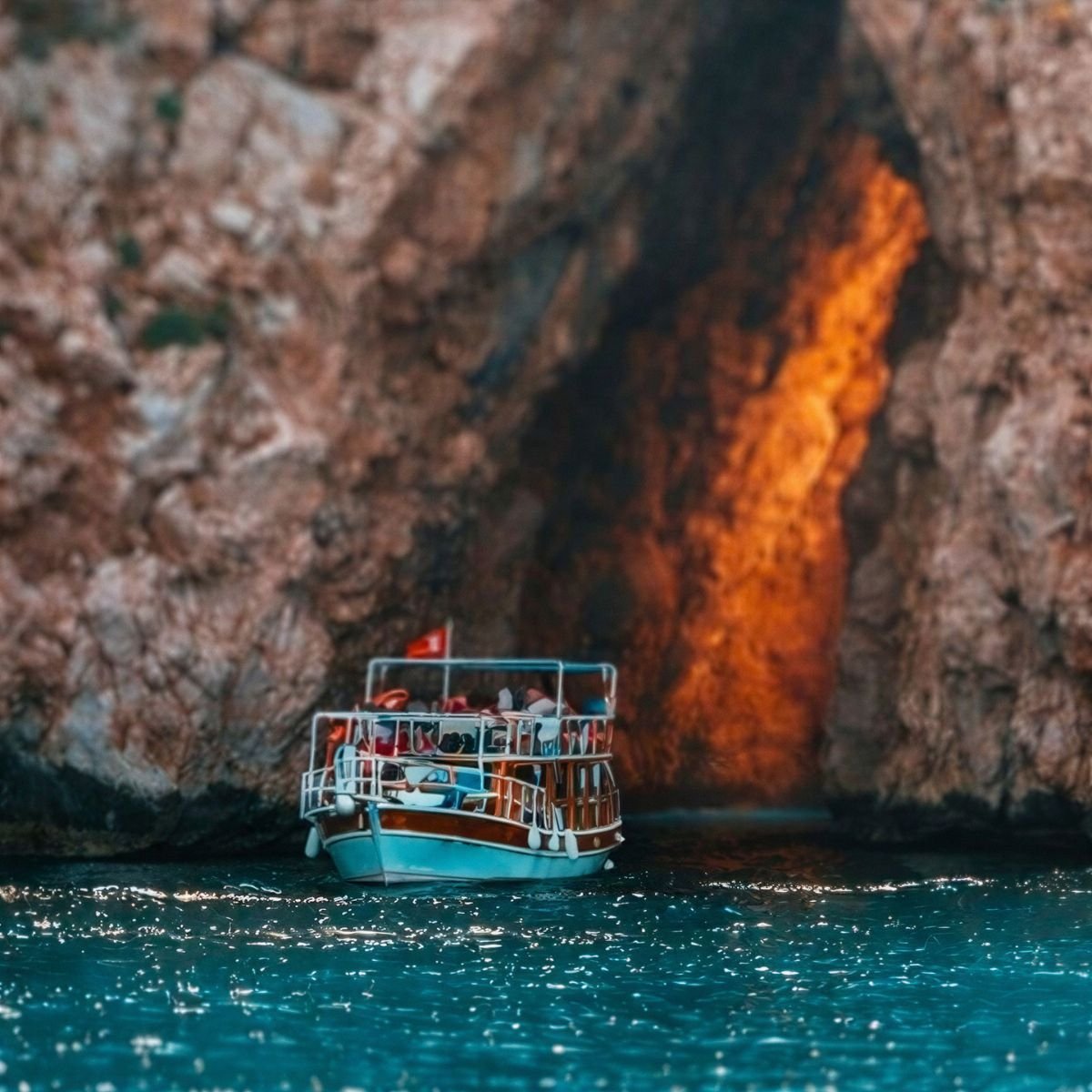Boat next to sunlit sea cave