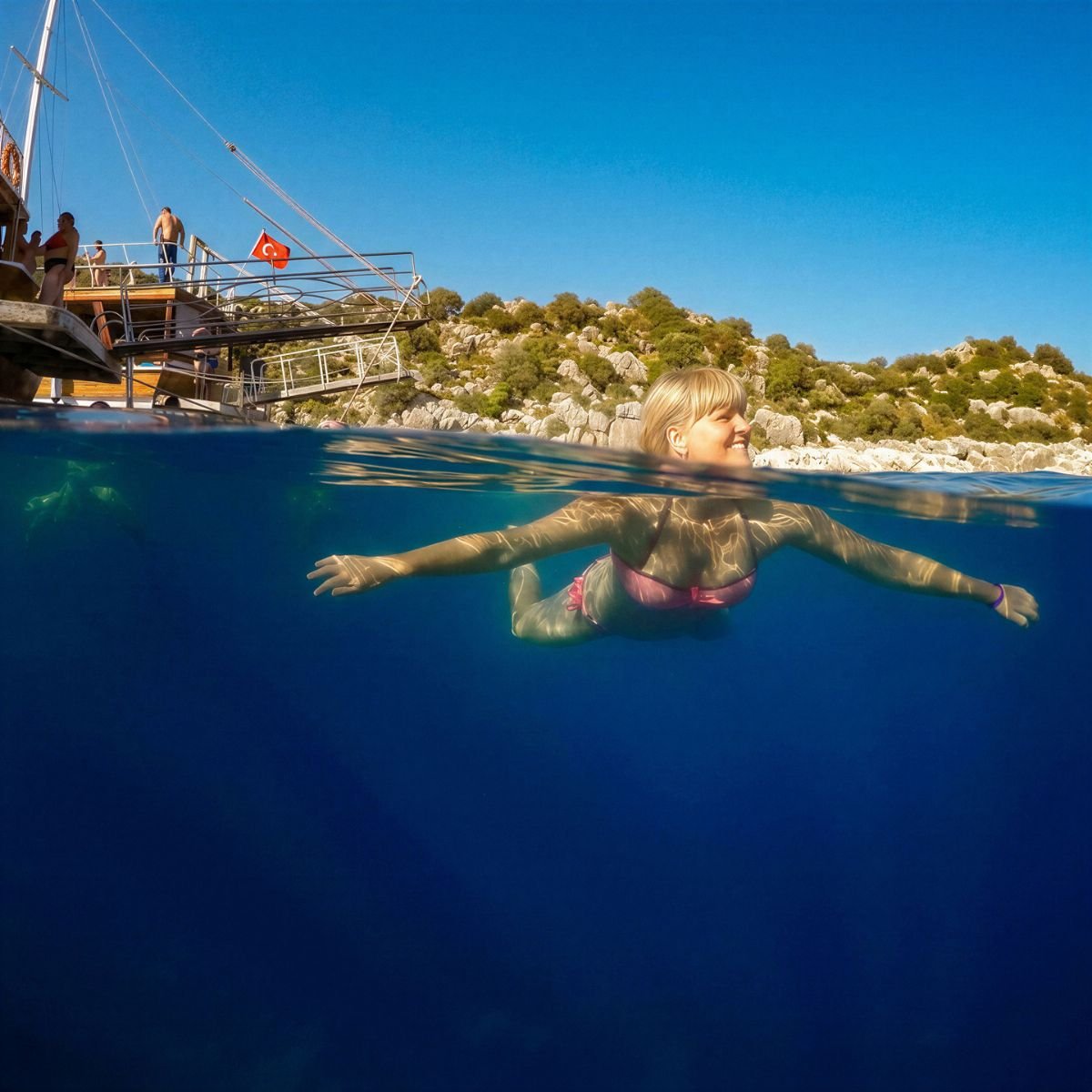 Swimmer in clear water beside gulet